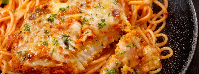 Chicken topped with cheeses and spaghetti in a tomato sauce
